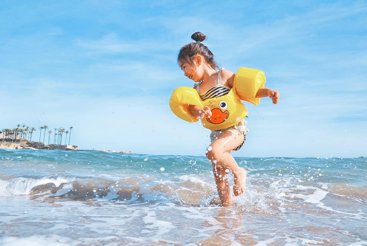 Man putting hearing aids child playing by the water on a beach